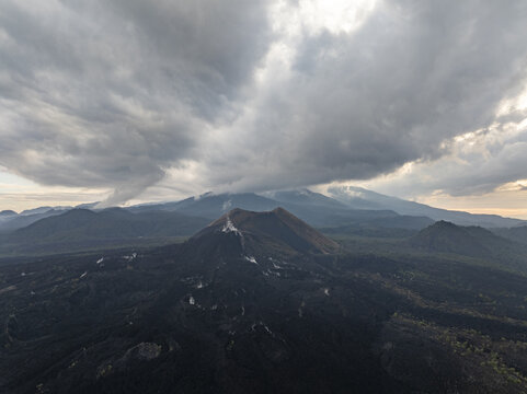 Aerial view of Paricutin volcano with its iconic volcanic cone and surrounding vast lava fields under a dramatic cloudy sky in San Juan Parangaricutiro, Michoacan, Mexico.