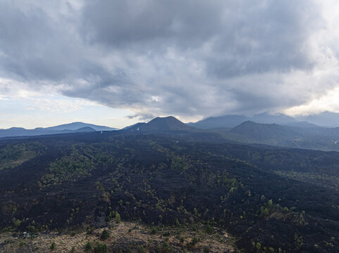 Aerial view of Paricutin volcano surrounded by vast volcanic lava fields and sparse vegetation under a dramatic cloudy sky in San Juan Parangaricutiro, Michoacan, Mexico.