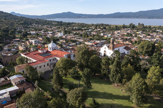 Aerial view of the historic Ex-Convento de Santa Ana with red-tiled roofs and church tower, surrounded by trees and the town of Tzintzuntzan, Tzintzuntzan, Michoacan, Mexico.