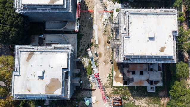Aerial view of a residential construction site with a tower crane and newly built apartment buildings in San Donato Milanese, Lombardy, Italy.