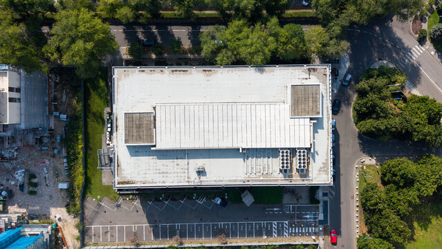 Aerial view of Eni Corporate University - Sede di Milano with its flat rooftop, HVAC units, and adjacent parking lot in San Donato Milanese, Lombardia, Italy.