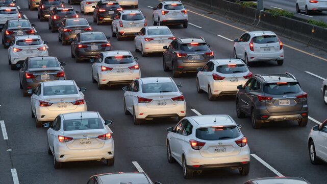 Heavy rush hour traffic congestion on a multi-lane highway with cars slowly moving in a queue, representing daily commuting challenges, air pollution, and urban gridlock