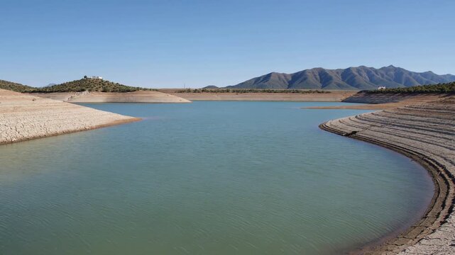 Scenic landscape showing extremely low water levels in a reservoir due to prolonged drought, highlighting the impact of climate change on natural resources and water scarcity