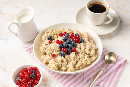 Oatmeal porridge bowl with fresh berries and cup of espresso black coffee