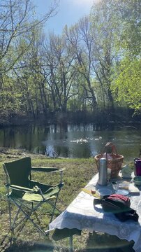 Folding chairs and a picnic table are set up on the riverbank. A panoramic view of the river. An atmospheric spot for relaxing in nature, solitude, and family time outdoors
