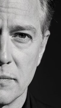 Vertical video: Speaking after mouth opening, middle-aged man in studio closeup wearing dark shirt