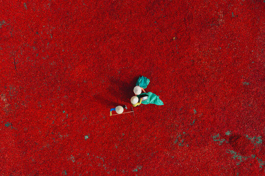 Aerial view of a worker with a conical hat sorting red chilies drying in De Gi, Binh Dinh, Vietnam