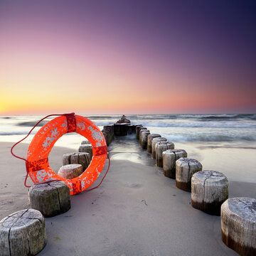 Long Rustic Wooden Groyne with lifebuoy on a White Sandy Baltic Beach at Sunset