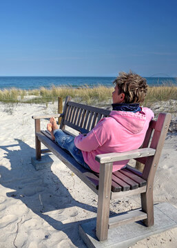 Woman Relaxing on an Old Wooden Bench Overlooking the Baltic Sea