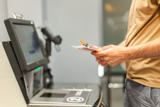 Customer holding packaged product at self-checkout kiosk