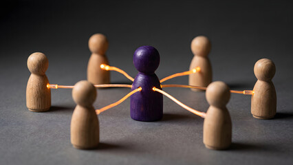 Obraz premium Purple leadership figure connected to a team of wooden dolls with glowing fiber optic cables representing network communication and teamwork