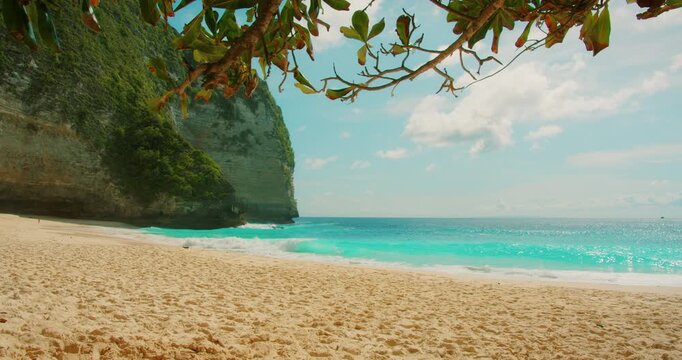 Wide view of empty tropical beach with golden sand and turquoise ocean water