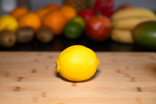 Lemon on a cutting board in the kitchen, citrus fruit. Fruits and vegetable in the background. Raw food, citrus fruit, healthy eating, organic, ripe, ready to eat.