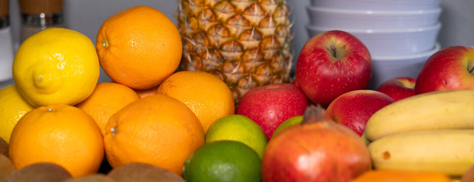 Various fruits like pineapple, orange, apple, lemon, banana on the table in the kitchen. Raw food, healthy eating, vegetarian food, organic, ripe, ready to eat.