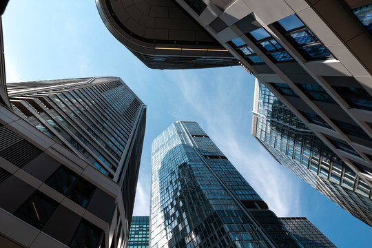 Low angle view of skyscrapers in Frankfurt am Main cityscape. Residential and office buildings against a blue sky, modern architecture, building exterior.