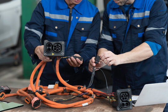 Electric vehicle car auto services. EV Wire Harness, High Voltage Cable, Portable Charger. Electrician checks or diagnostic wire harnesses for electric vehicle or EV car in auto workshop