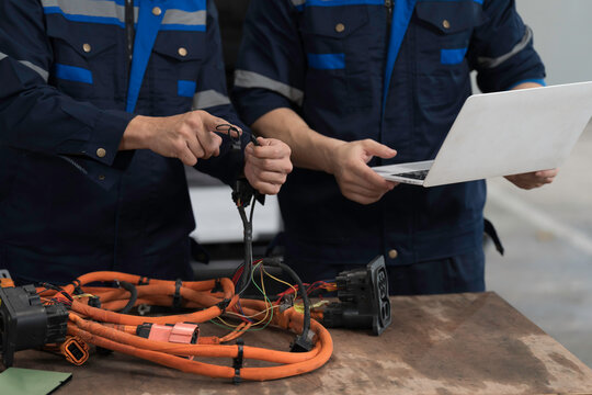 Electric vehicle car auto services. EV Wire Harness, High Voltage Cable, Portable Charger. Electrician checks or diagnostic wire harnesses for electric vehicle or EV car in auto workshop