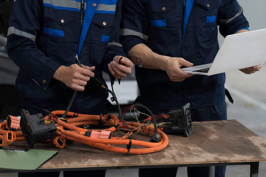 Electric vehicle car auto services. EV Wire Harness, High Voltage Cable, Portable Charger. Electrician checks or diagnostic wire harnesses for electric vehicle or EV car in auto workshop