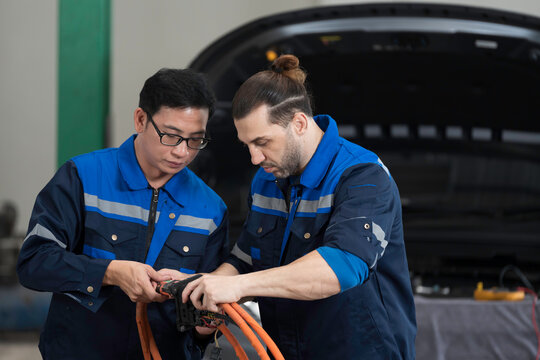 Electric vehicle car auto services. EV Wire Harness, High Voltage Cable, Portable Charger. Electrician checks or diagnostic wire harnesses for electric vehicle or EV car in auto workshop