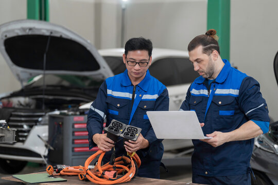 Electric vehicle car auto services. EV Wire Harness, High Voltage Cable, Portable Charger. Electrician checks or diagnostic wire harnesses for electric vehicle or EV car in auto workshop