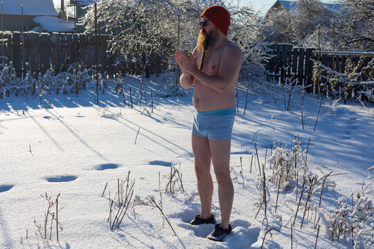 A naked man is meditating in the snow in winter.