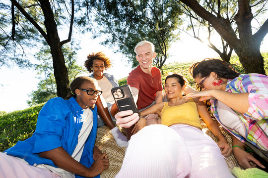 Group of friends lying over blanket in a park using smartphone
