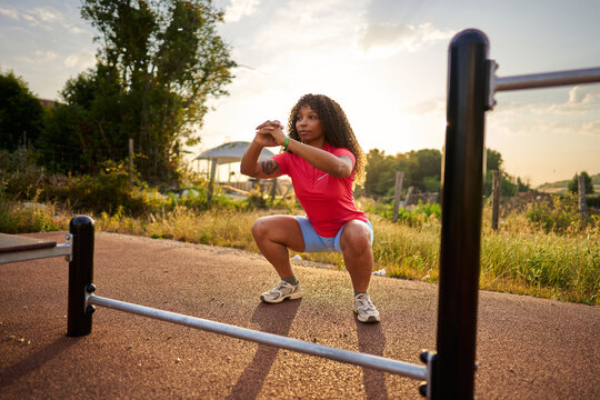 Woman exercising outdoors, doing squats during sunset workout