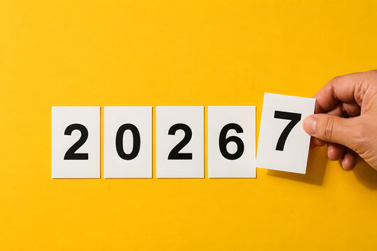A hand placing card with number seven changing year to 2027.