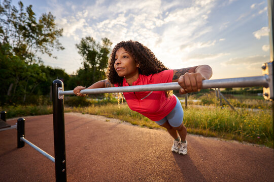 Woman training calisthenics outdoors doing horizontal push ups