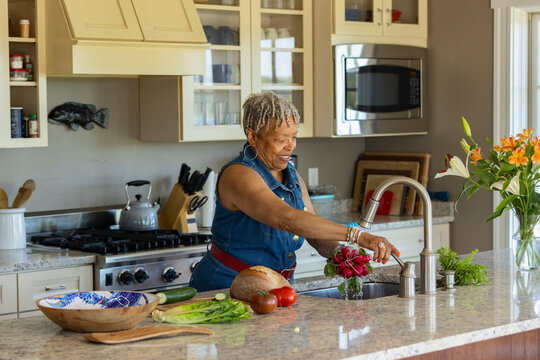 Senior Black black alone woman prepare meal kitchen home 