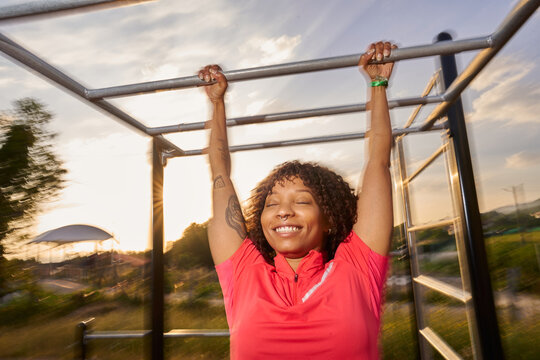 Woman exercising on monkey bars enjoying sunset workout