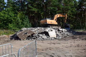 Heavy tracked excavator standing on pile of crushed concrete debris © Olesia