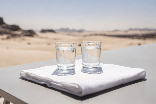 Two Glasses of Water on White Towel in Desert Landscape