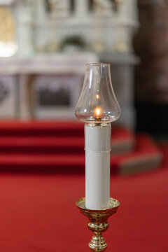A candle burns on the altar during a holy mass at a catholic church. Worshippers gather for the religious ceremony in faith.