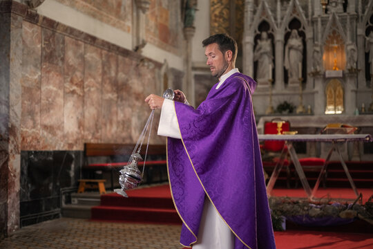 A catholic priest performs a religious ceremony with burning incense. He holds a smoking censer while preparing for the mass.