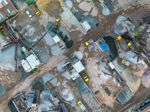 Aerial view of an industrial sand and gravel processing site featuring heavy machinery, conveyor belts, and dump trucks loading materials in Dhaka, Dhaka Division, Bangladesh.