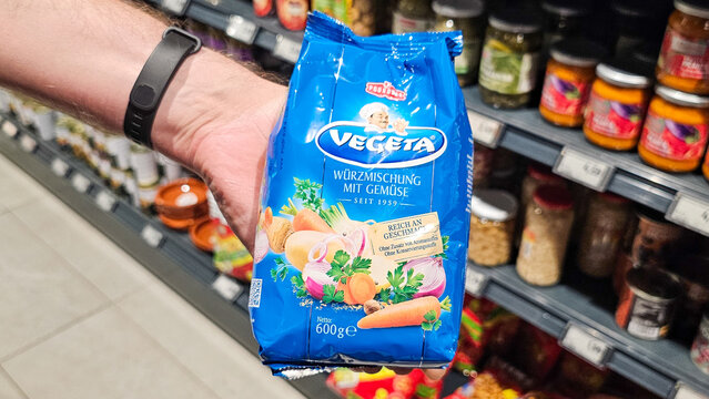 Hand holding vegeta spice blend in supermarket aisle