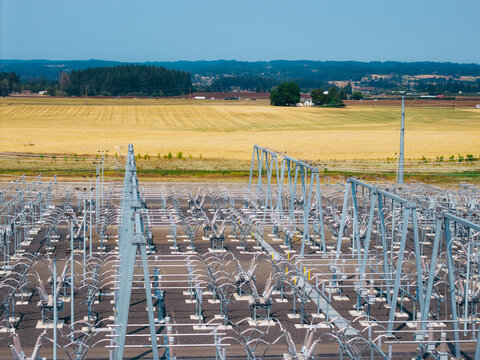 Aerial view of the Hillsboro substation with metal structures and electrical equipment set against golden farmland and distant trees under a clear blue sky in Hillsboro, Oregon, United States.