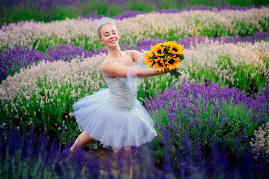 Ballerina dancing with sunflower bouquet in lavender flower field