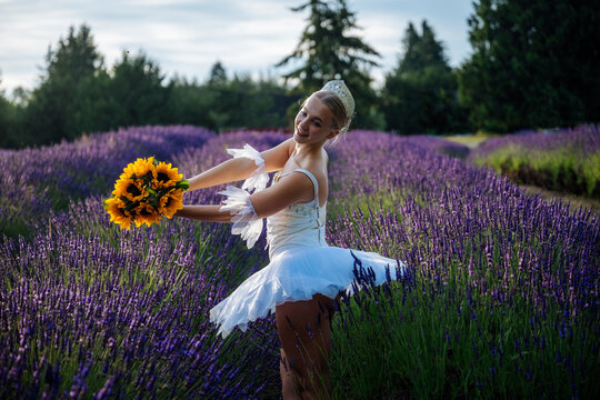 A ballerina in a white tutu poses with sunflowers in a lavender field