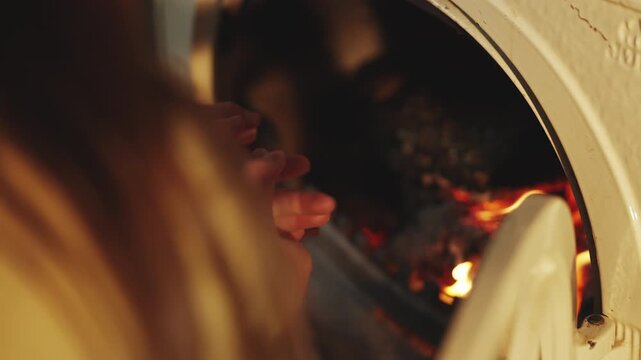 Cheerful children warm their hands by fireplace at home on a cold winter day