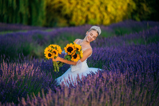 A woman in white holding sunflower bouquets in a lavender field