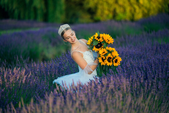Ballerina in white tutu holds sunflowers in lavender field