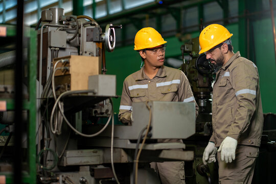 Team of industrial worker is checking the setup value of  metal casting machine by automated monitor while working inside factory for safety industry
