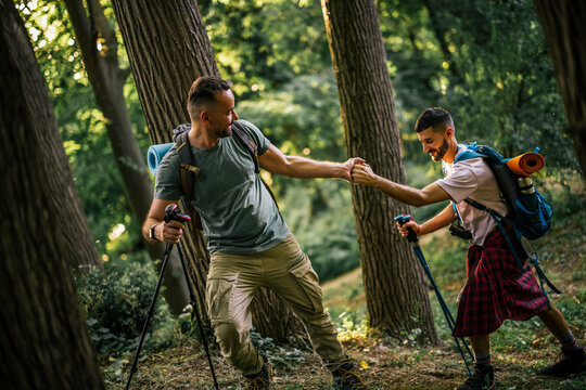 Hikers helping each other cross a forest trail during an outdoor adventure