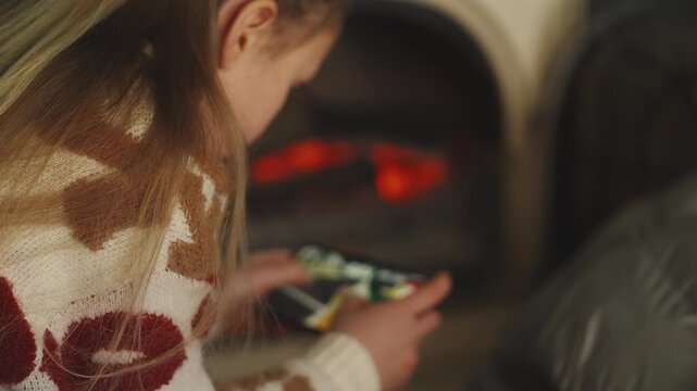 Little girl plays racing video game on her phone at home, digital lifestyle