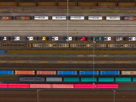 Aerial view of a busy railway yard featuring various freight trains, colorful cargo containers, and tanker cars lined up on parallel tracks in Breclav, South Moravian Region, Czechia.