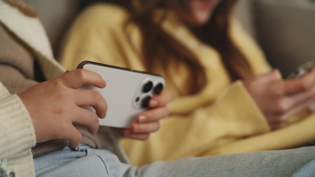 Two siblings play online video game on their phones, excessive screen time