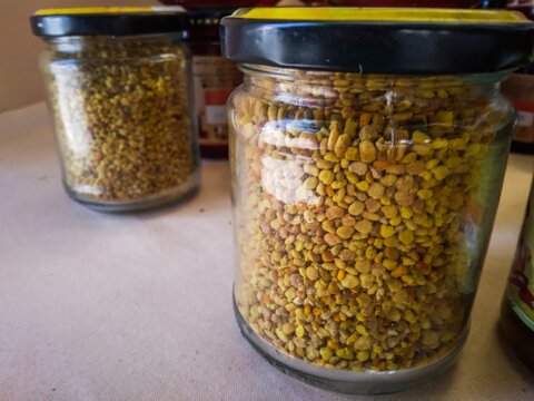 Glass jars filled with golden bee pollen granules for healthy natural nutrition.