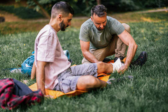 Hiker receiving ankle treatment while resting on a mat outdoors